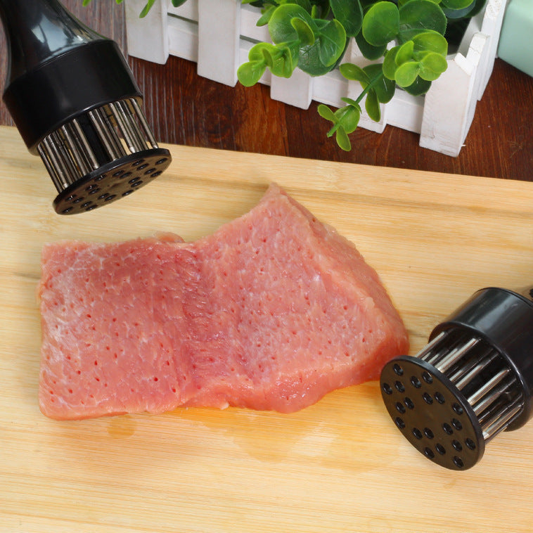 Raw meat on a wooden cutting board with two meat tenderizers on either side.