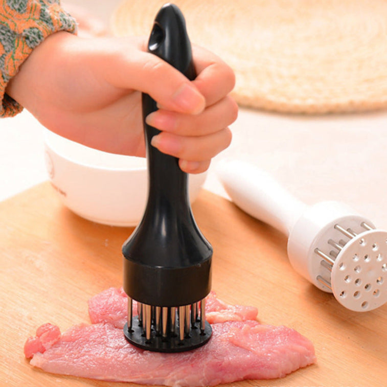 Hand using a meat tenderizer on a piece of meat with a pepper grinder in the background.