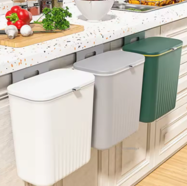 Three wall-mounted trash bins in white, gray, and green on a kitchen counter.