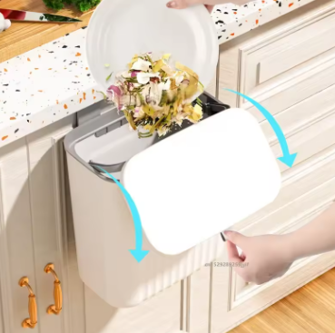 Wall-mounted trash can with a lid being opened, showing waste inside.
