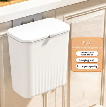 White wall-mounted trash can with a lid on a wooden cabinet.
